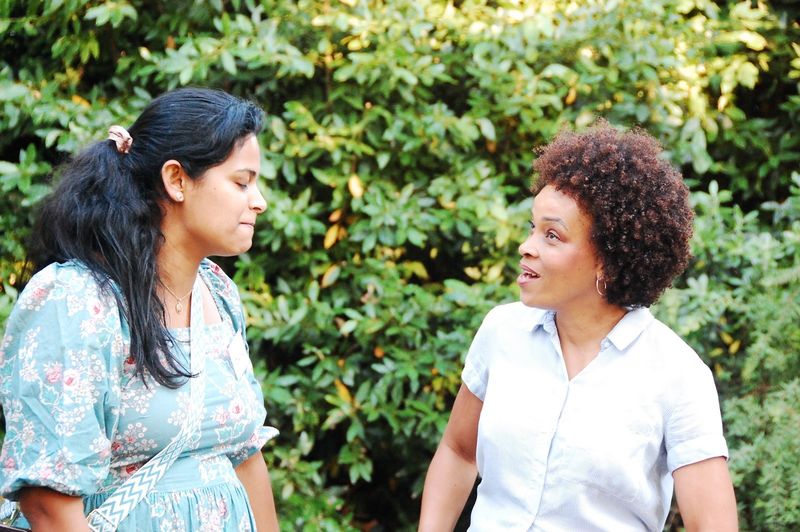 Two guests talking together in front of the garden greenery.