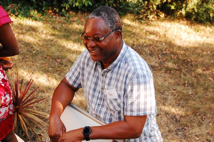 A guest smiling as he carries a folding table across the garden.