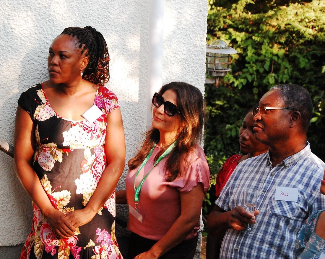 Four guests standing together, listening, drinks in hand.